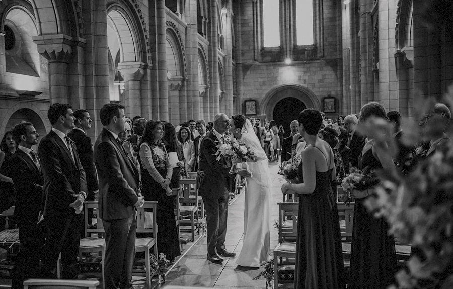 The bride kisses her father in the aisle of the church