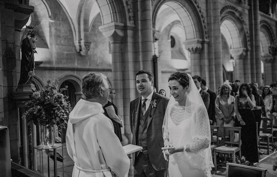 The bride laughs with the vicar in church during the wedding ceremony