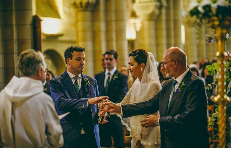 The groom takes the hand of the bride during the ceremony