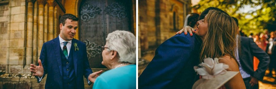 A wedding guest hugs the groom outside church at St. Benets Minster in Suffolk