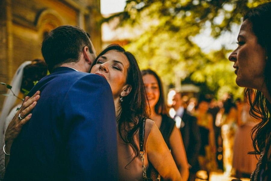 A wedding guest hugs the groom outside church