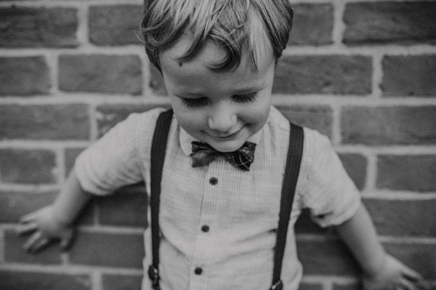 A portrait of a boy against a wall looking down at his feet