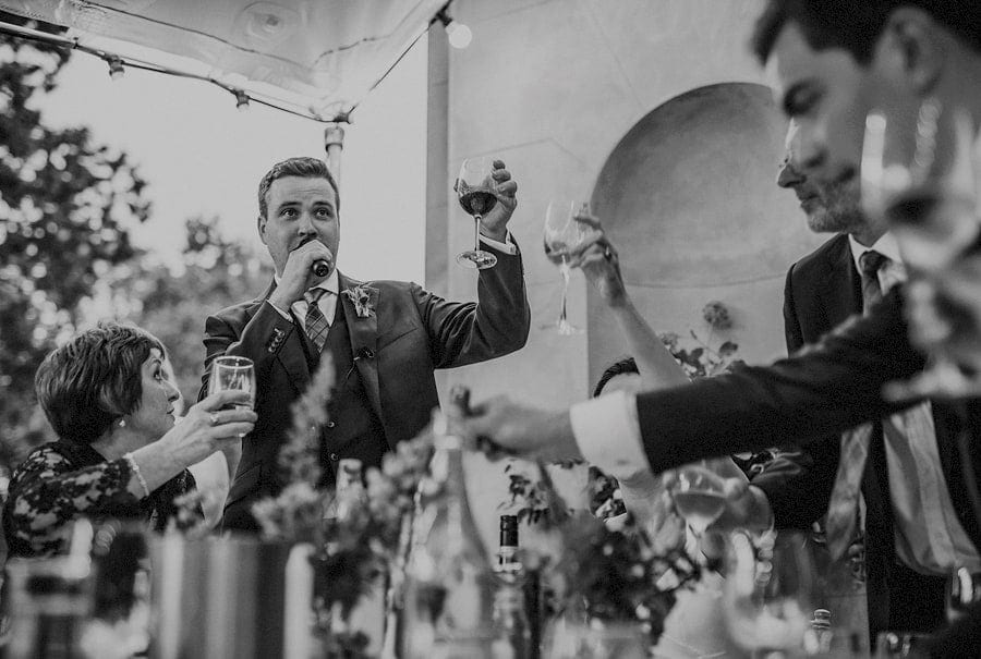 The groom raises his glass and toasts to his wife