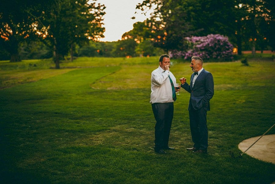 Two men outside the marquee smoke cigars on the lawn at Wilderness Reserve