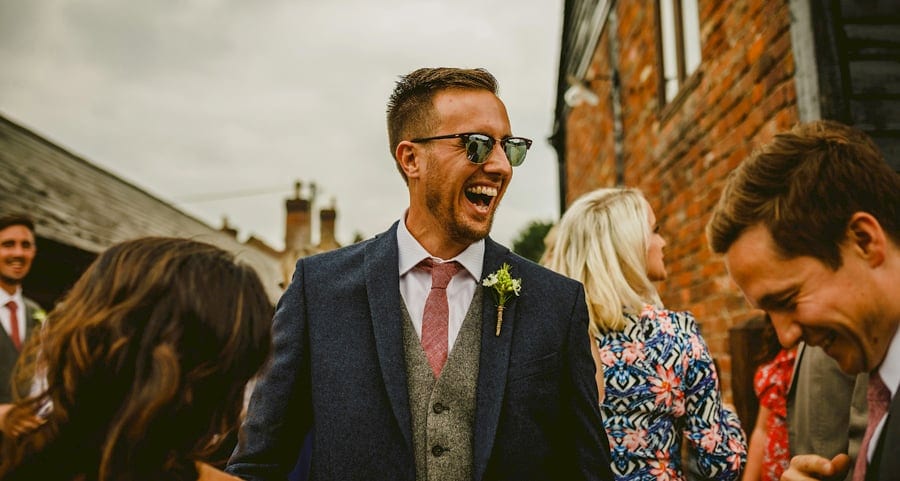 An usher laughs at a joke told by a friend in the courtyard at Over Barn