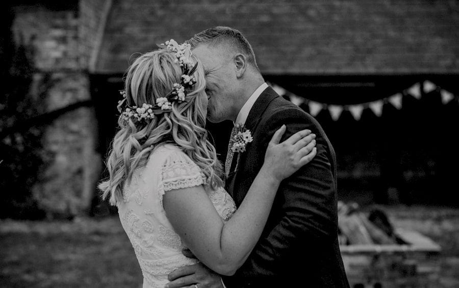 The bride and groom kiss each other at the end of the outdoor wedding ceremony