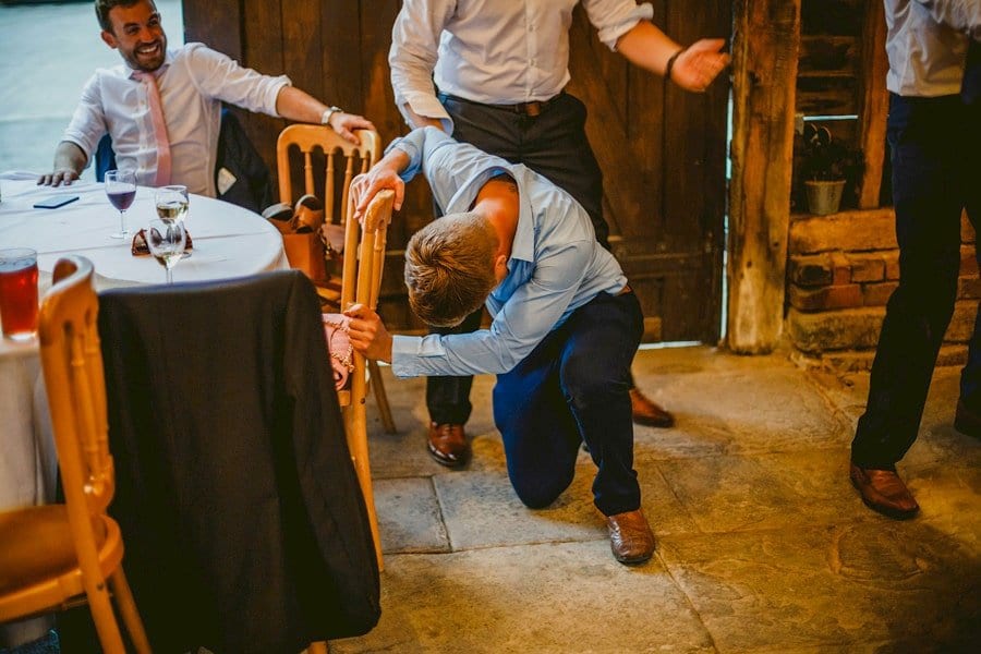 A wedding guest falls onto the floor and attempts to get up in the barn