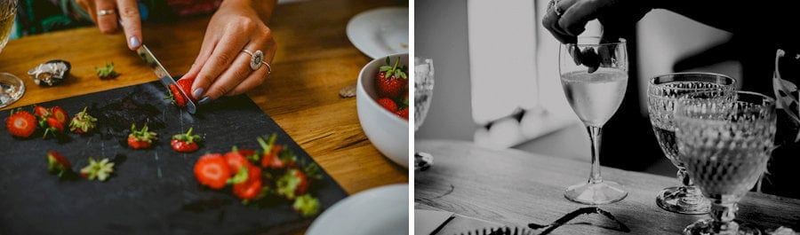 A lady chops up strawberries on a large grey slate and places them into the champagne