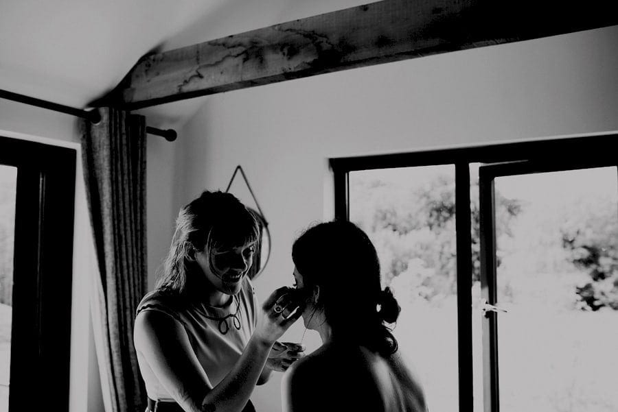 The makeup artist applies mascara to the brides face in the cottage at Yurt retreat in Crewkerne, Somerset