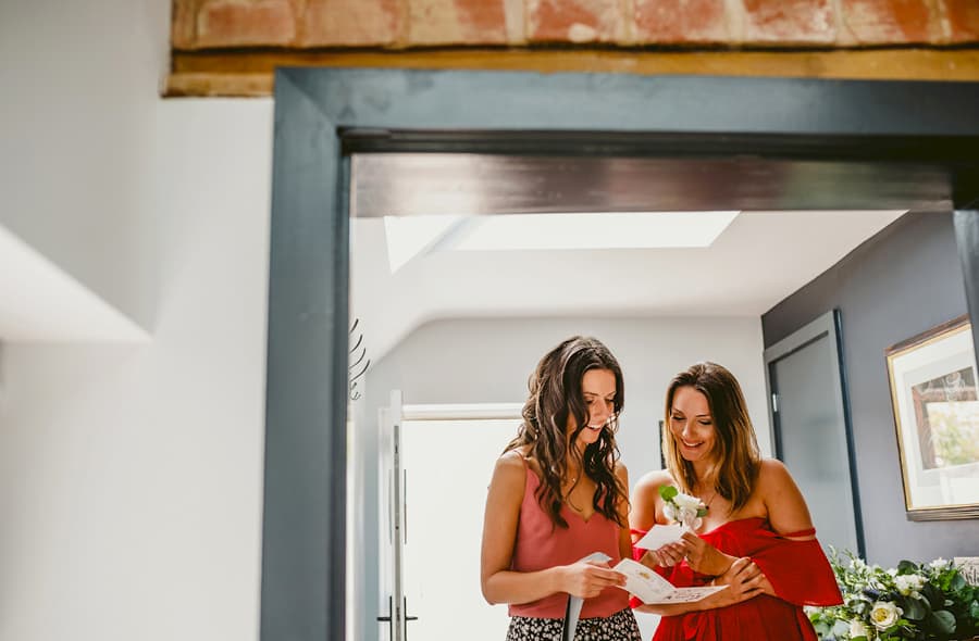 The bride and a bridesmaid read a letter written by the groom in the hallway of the cottage