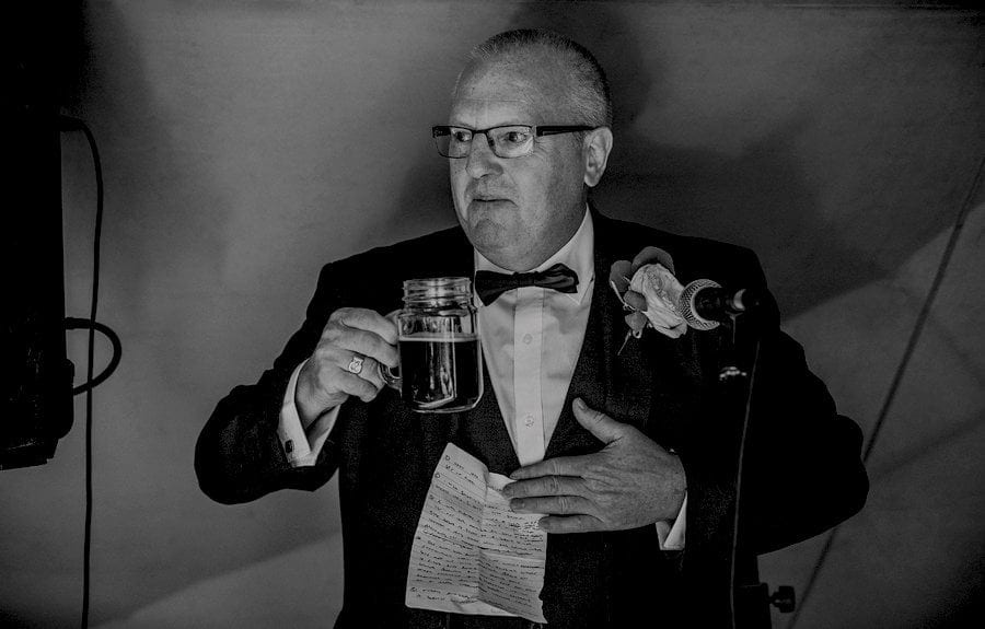 The bride's father holds a drink in his hands and starts his wedding speech in the tipi at yurt retreat