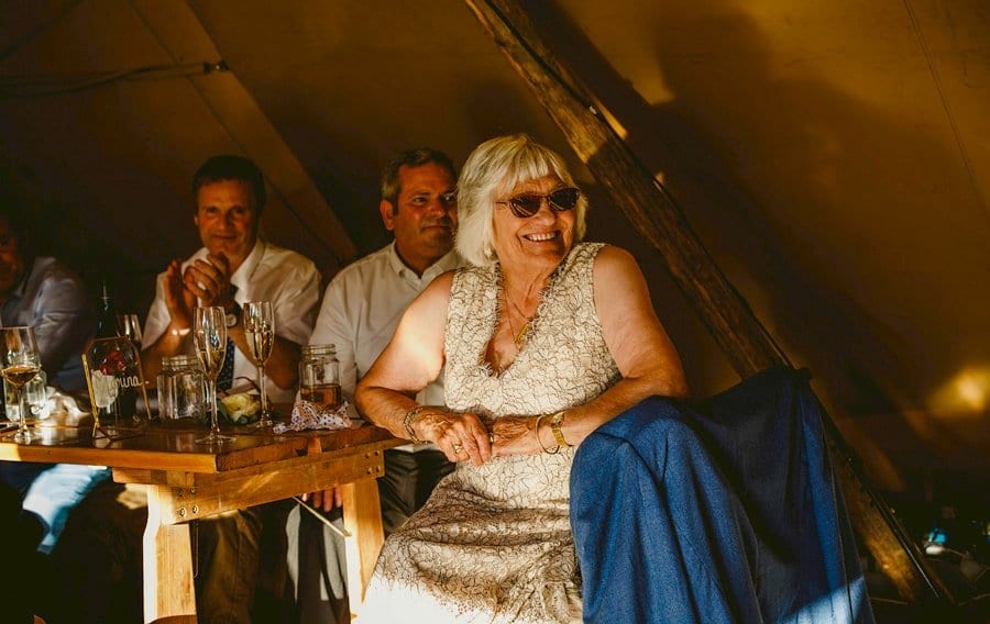 The brides grandmother laughs at one of the speeches in the tipi