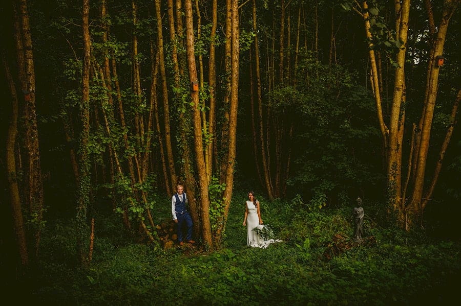 The bride and groom pose for a photograph as they stand next to each other in the woods at the Yurt Retreat in Crewkerne, Somerset