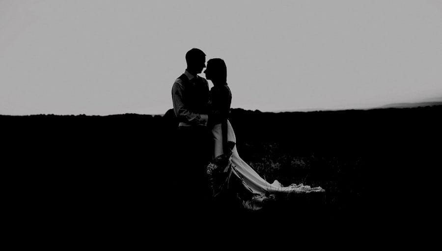 The bride and groom stand on top of the hill and hold each other at the Yurt Retreat in Somerset
