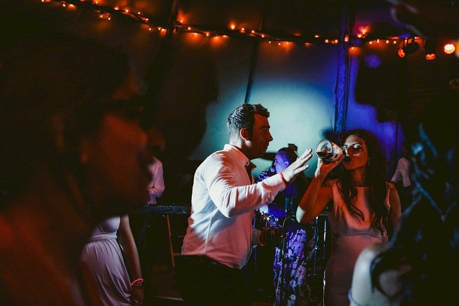 The bride drinks a bottle of alcohol on the dancefloor in the tipi