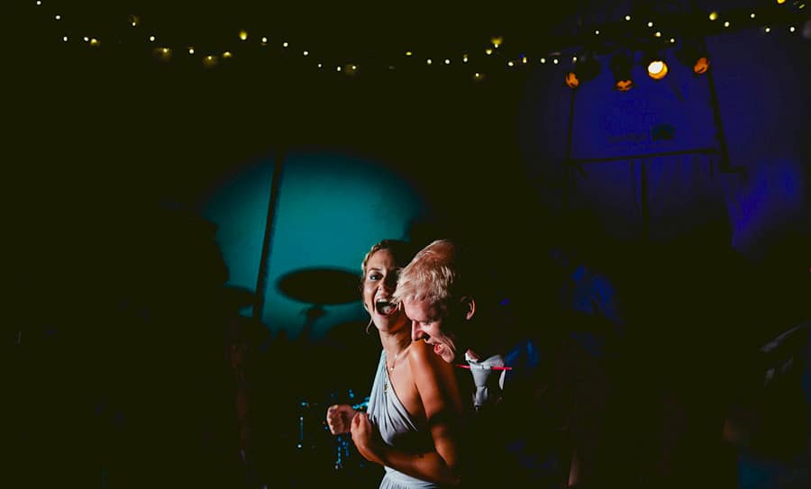 The groom puts his arms around a bridesmaid on the dancefloor in the tipi at yurt retreat