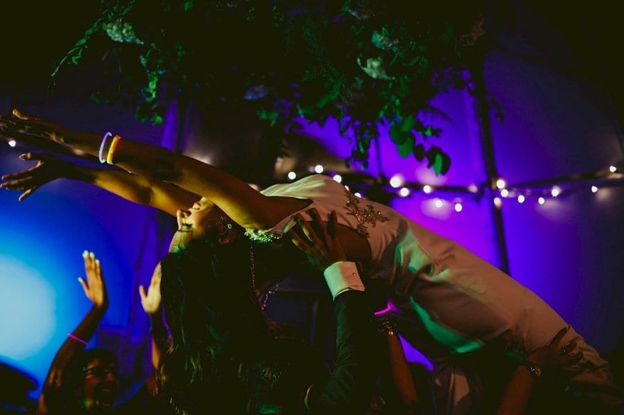 Wedding guests raise the bride in the air on the dancefloor in the tipi