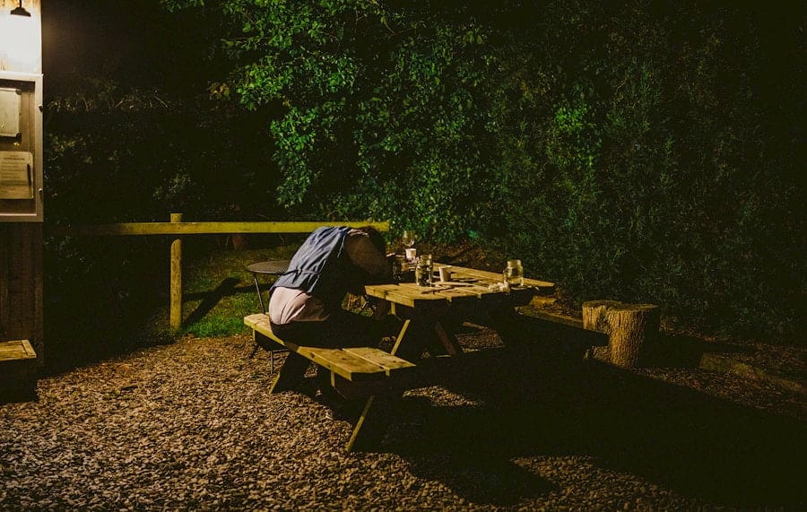 A man lies asleep on a wooden bench outside the tipi at yurt retreat in Crewkerne