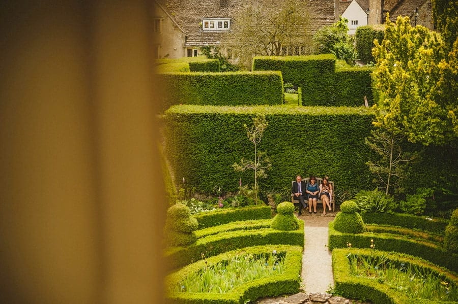 Wedding guests sitting on a bench in Abbey House Gardens