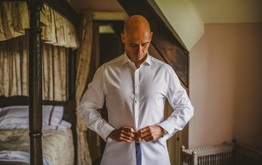 The groom fastens a button on his shirt
