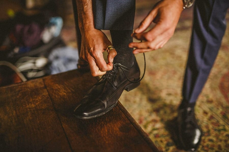 The groom ties his shoe laces in one of the rooms at Abbey House Gardens in Malmesbury