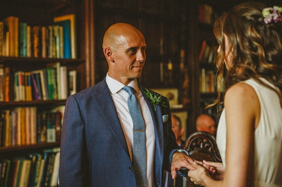 The bride holds the grooms hand during the wedding ceremony at Abbey House