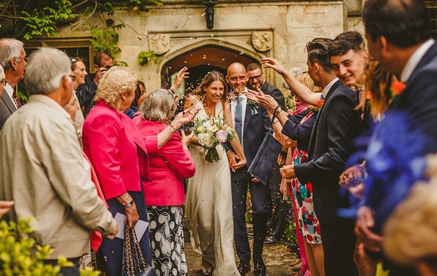 Wedding guests throw confetti over the bride and groom at Abbey house Gardens