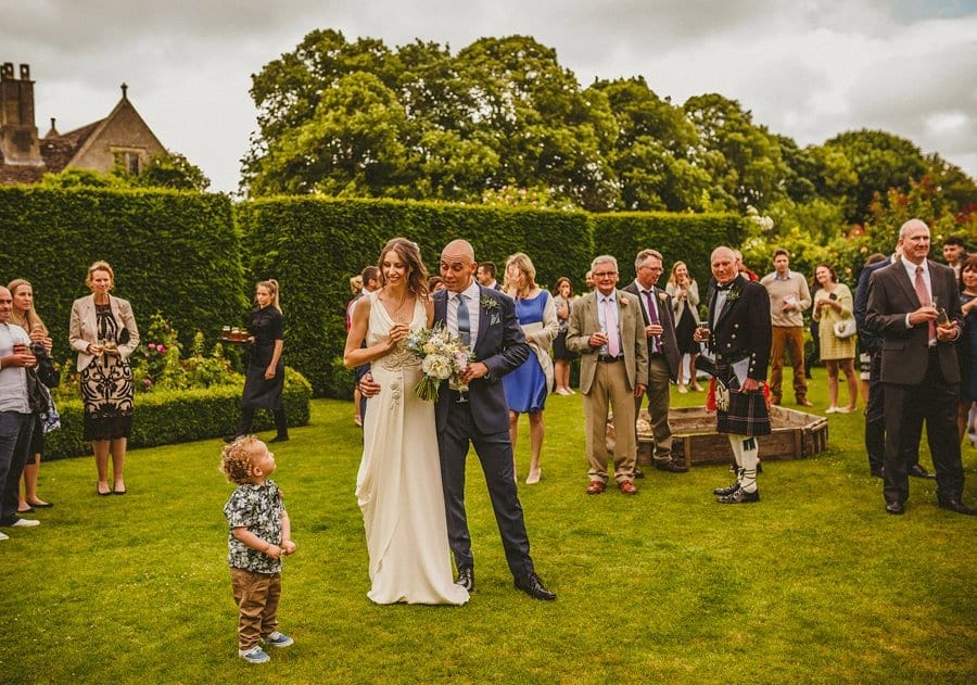 The bride and groom listen to their son in the gardens at Abbey House