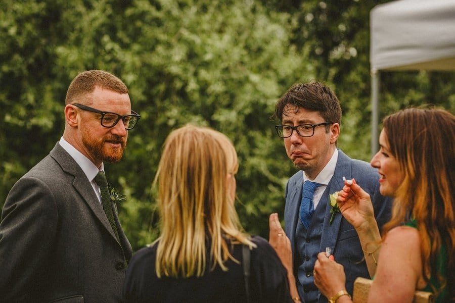 A wedding guest pulls a face as he listens to another wedding guest