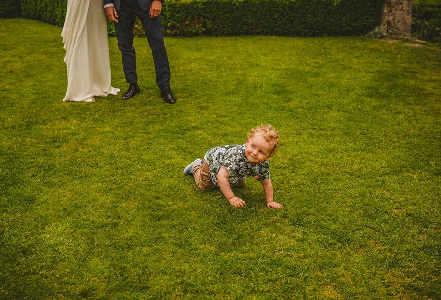 The bride and grooms son crawls along the grass in the gardens at Abbey House