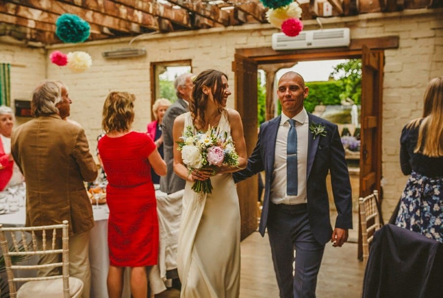 The bride and groom enter the room and wedding guests stand and clap