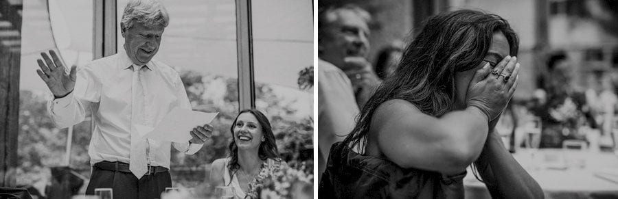 A wedding guest holds her hands in her face and laughs as the brides father delivers his speech