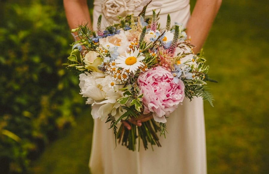 The bride holds her flower bouquet with both hands