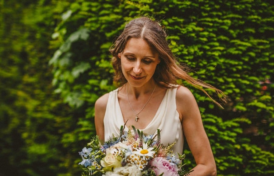 The bride looks down on the floor and holds her wedding bouquet
