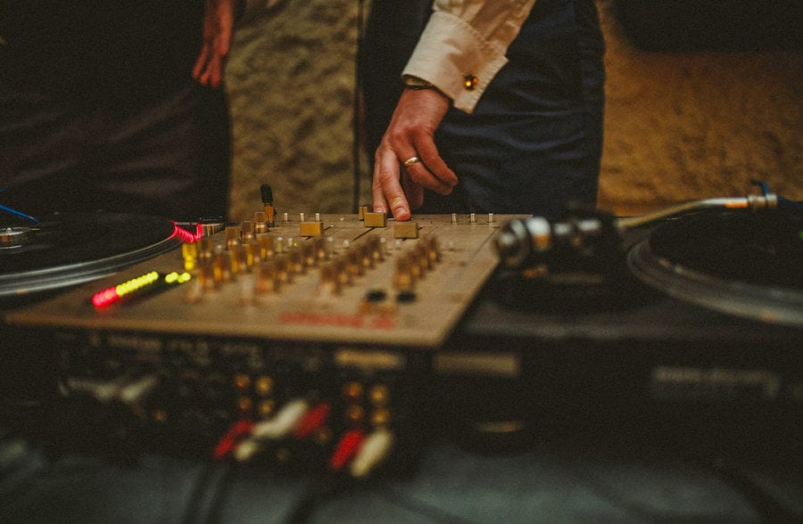 The DJ places his fingers on the mixing desk