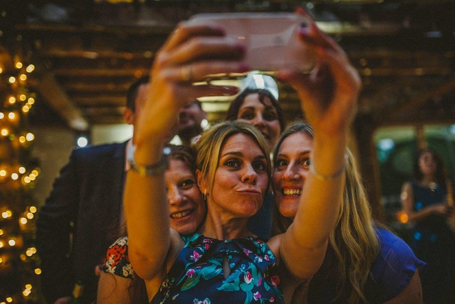 A lady holds up a mobile phone and takes a photograph of herself and her friends on the dancefloor
