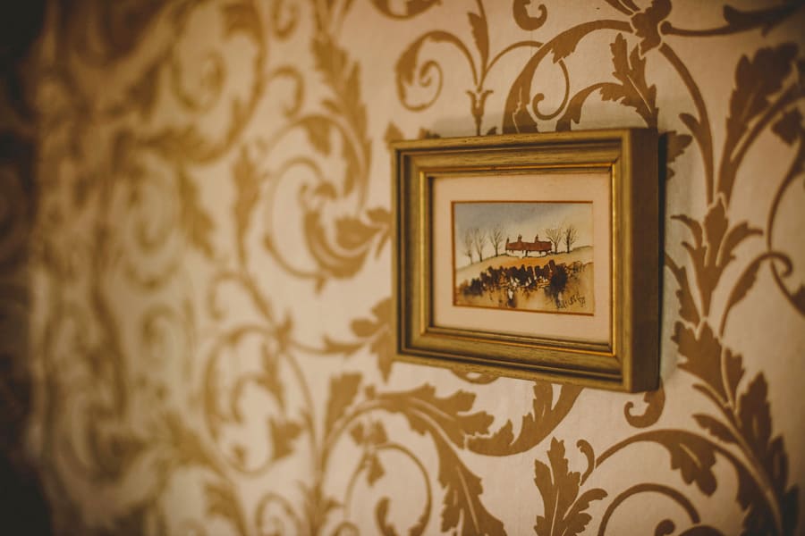A framed oil painting hangs from a wall in a cottage