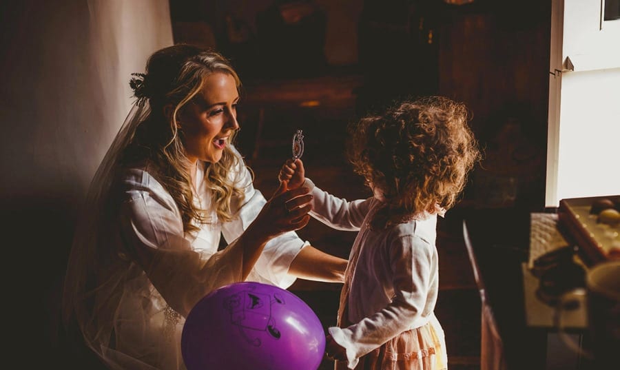 The bride bends down and talks to her niece who shows the bride and toy