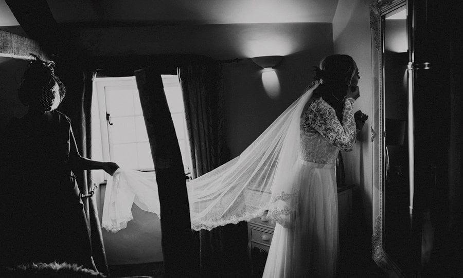 The bridesmaid puts on earrings as she looks in the mirror in the bedroom