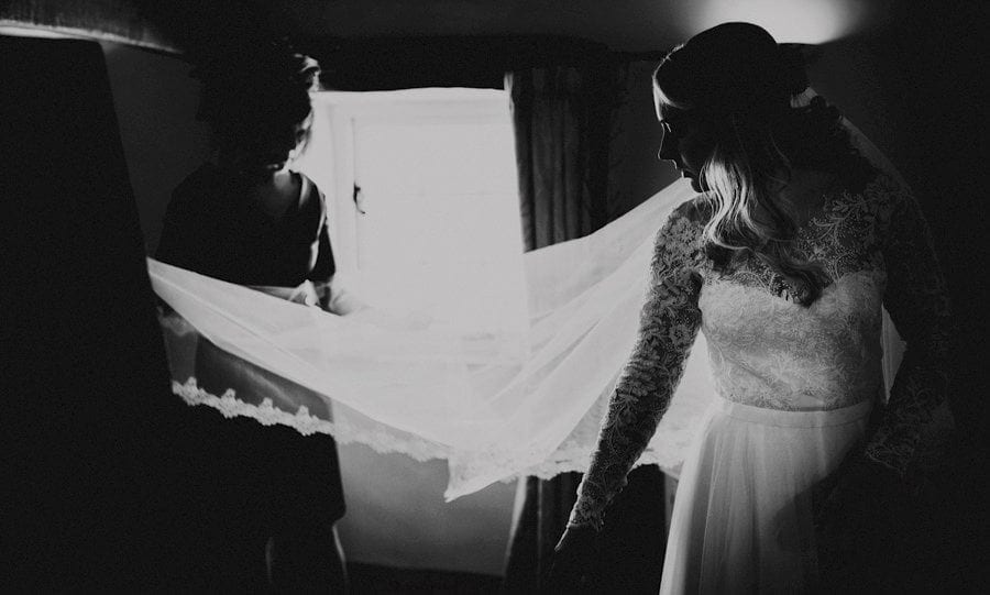 The bridesmaids hold the brides veil in their hands as the bride watches