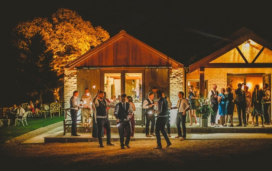 Wedding guests light sparklers outside Eden Barn in the evening
