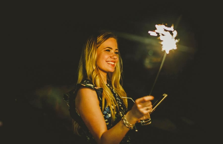 A wedding guest waves a sparkler in the air outside Eden Barn