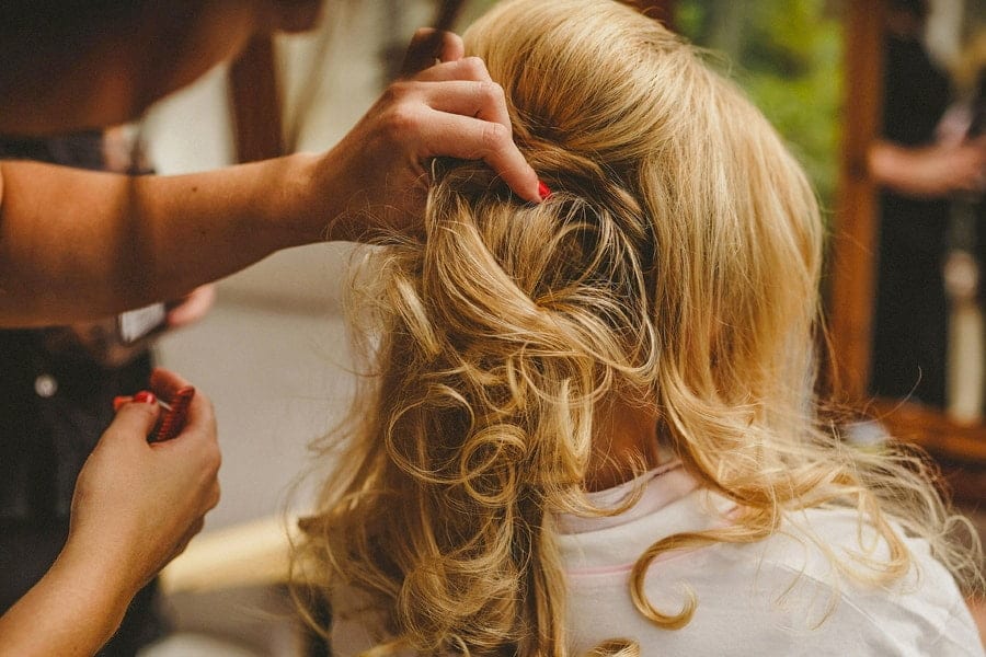 The make up artist holds the brides hair in place