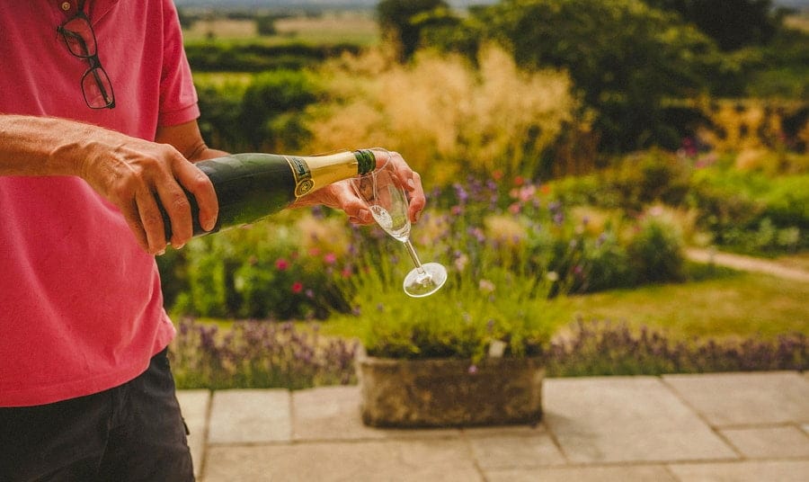 The brides father pours champagne into a glass