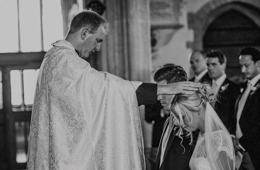 The vicar places a hand over the brides head in church
