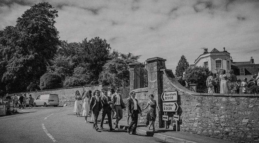 Wedding guests leave the church and walk along the roadside