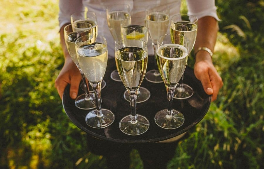 A waitress holds a tray full of flutes filled with champagne