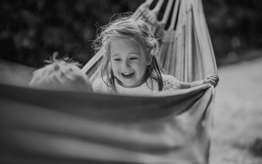 A flowergirl laughs with her brother in a hammock