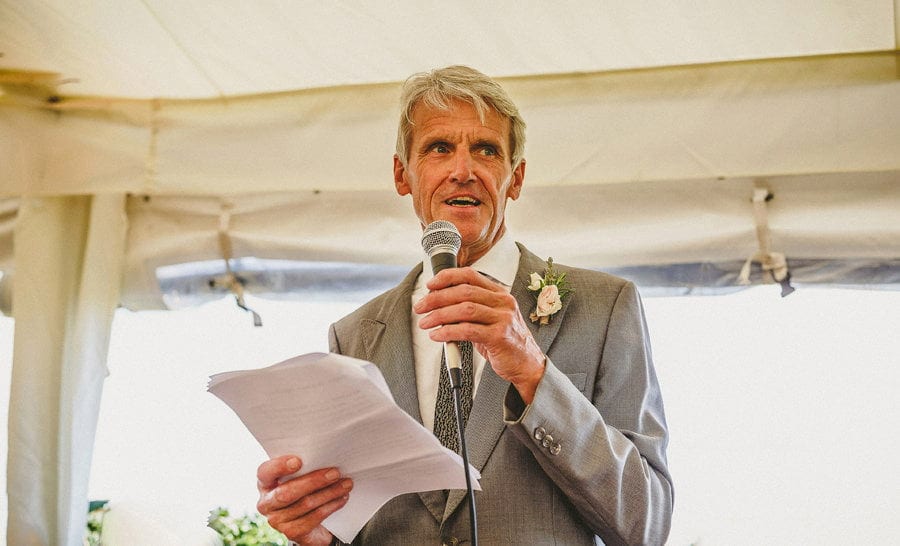 The brides father delivers his speech to the wedding party in the marquee