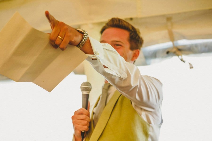 The groom points to an usher as he delivers his wedding speech in the marquee